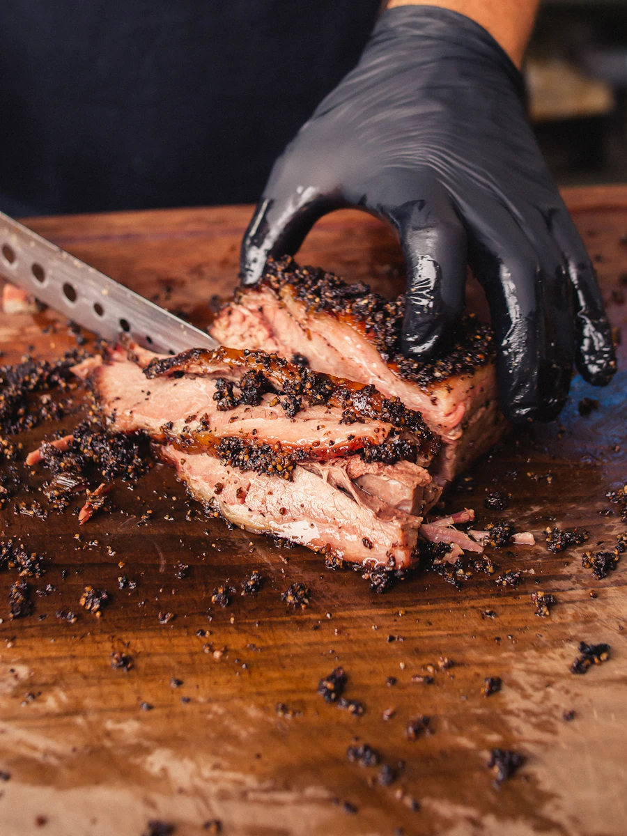 Hands slicing a bark-crusted brisket