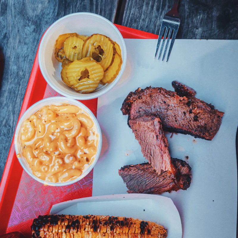A tray with corn, mac and cheese, and smoked meat