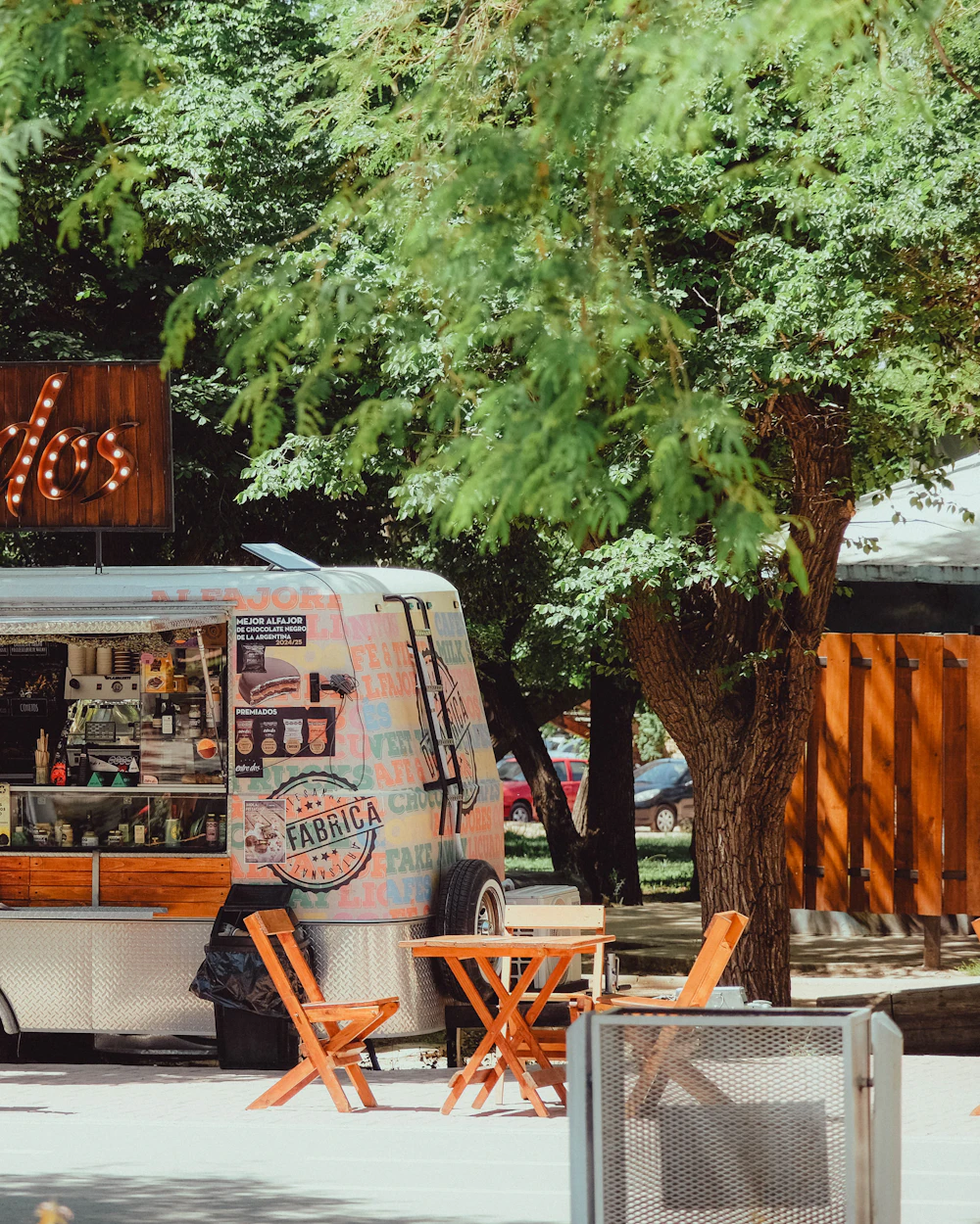 A vintage food trailer with picnic tables under trees